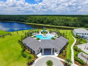 A golf course with a swimming pool, surrounded by lush greenery and a lake.