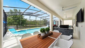 A covered outdoor area with a pool, seating, and a grill. - Themed Theater Room | Themed Kids Bedrooms | Games Area | Screened Pool (Kissimmee)