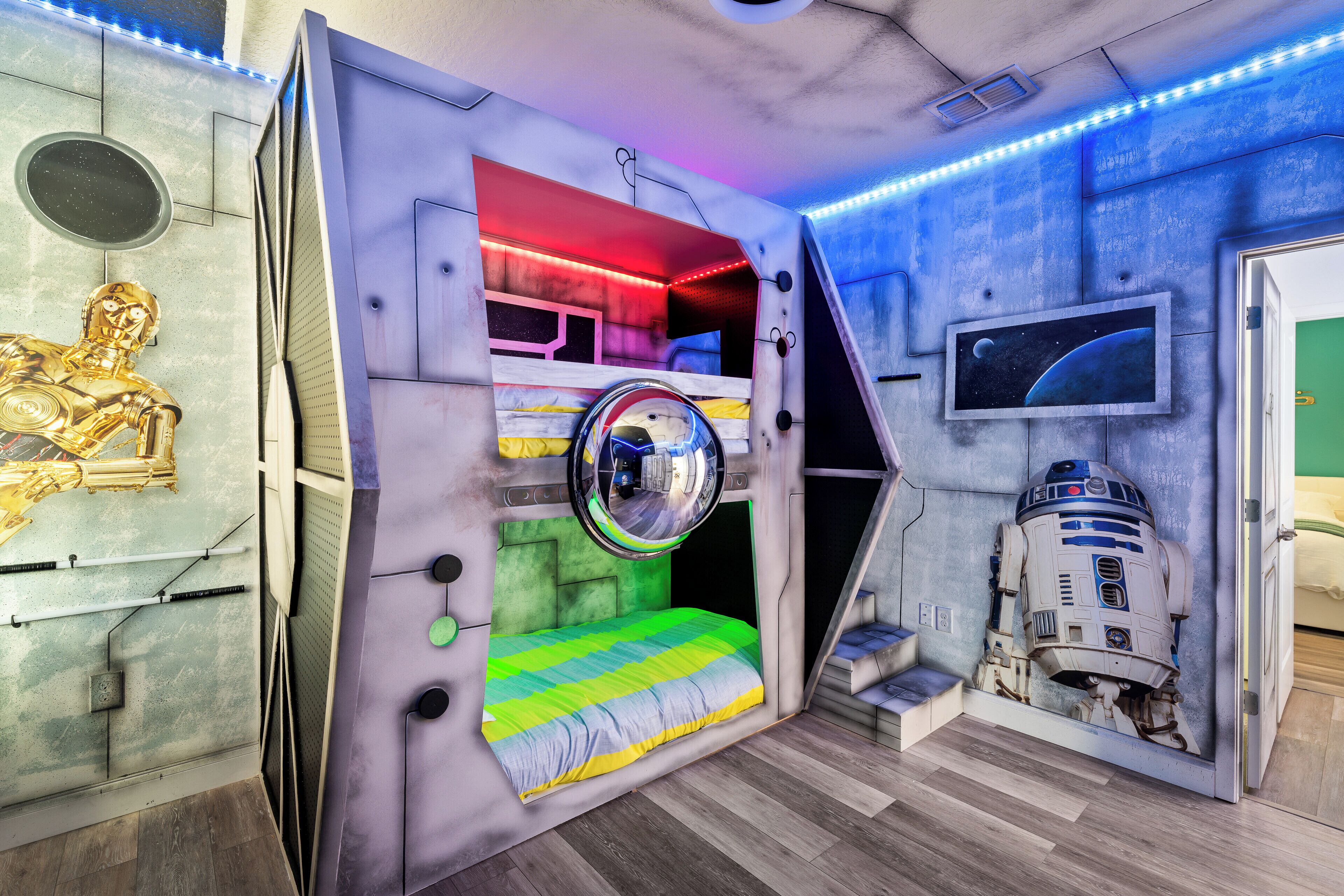Een kamer met een stapelbed, een plafondventilator, een tv aan de muur en een muurschildering met Star Wars thema.
