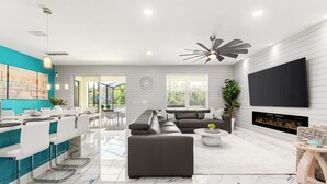 A modern living room with a sectional sofa, a flat-screen TV, and a fireplace. - Themed Theater Room | Themed Kids Bedrooms | Games Area | Screened Pool (Kissimmee)