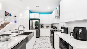 A modern kitchen with white cabinets, a stainless steel refrigerator, a built-in oven, and a coffee maker. - Themed Theater Room | Themed Kids Bedrooms | Games Area | Screened Pool (Kissimmee)