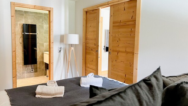 Ein Hotelzimmer mit Bett, Spiegel, Lampe und Holztüren.