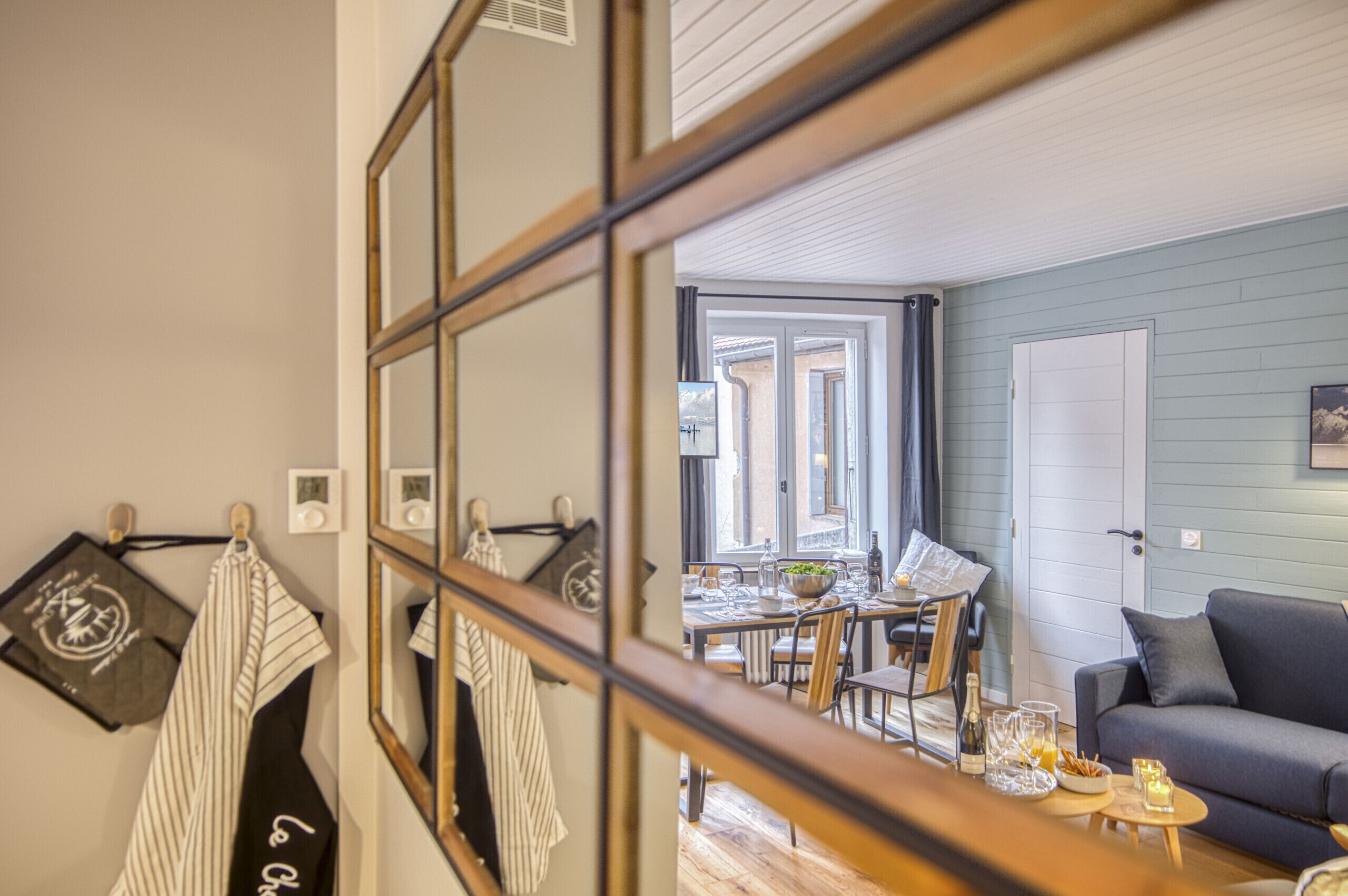 Une pièce comprenant un coin repas, un canapé et un miroir qui agrandit visuellement l’espace.