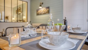 A dining table set with glassware, a candle, and a bowl with a spoon.