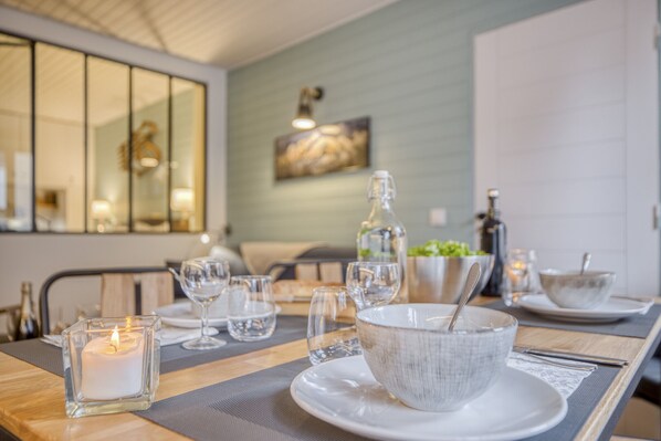A dining table set with glassware, a candle, and a bowl with a spoon.
