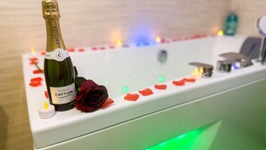 Eine Badewanne mit einer Champagnerflasche und einer Rose am Rand.