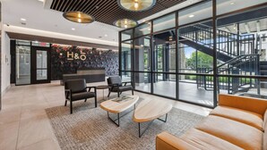 A modern hotel lobby with a reception desk, seating area, and large windows offering views of the outdoors.