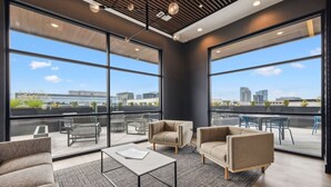 A modern office space with large windows, a high ceiling, and contemporary furniture.