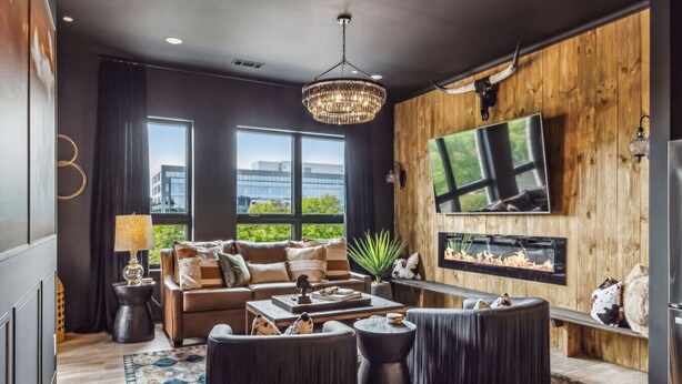 A modern living room with a fireplace, a large TV, and a view of the city.