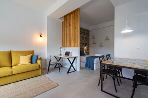 Ein modernes Wohnzimmer mit einem gelben Sofa, einem Esstisch mit Stühlen, einer Holzvertäfelung und einer Fliesenküchenzeile mit Muster.