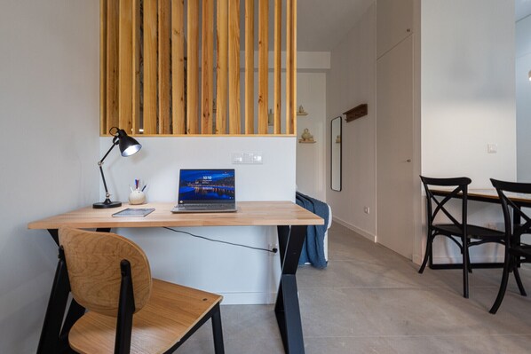 A modern office space with a wooden desk, a laptop, a desk lamp, and a chair.