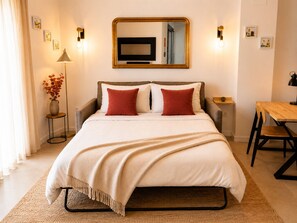 A hotel room with a bed, bedside tables, a desk, and a mirror.
