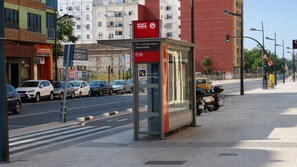 Un arrêt de bus avec un abri, une rue avec des voitures et des bâtiments en arrière-plan.