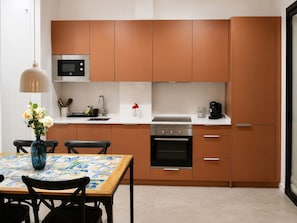 A modern kitchen with brown cabinets, a microwave, an oven, and a coffee maker.