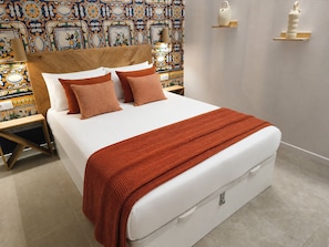 Una cama con cabecera de madera, ropa de cama blanca y una manta roja.