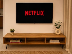 Un televisor de pantalla plana montado en la pared con la palabra 'NETFLIX' mostrada en la pantalla.