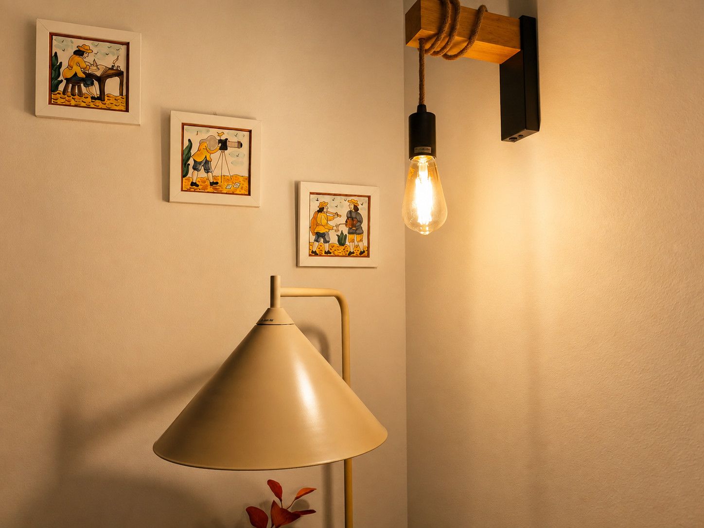 A room with a lamp, framed artwork, and a hanging light fixture.