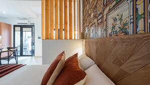 Une chambre d’hôtel avec un grand lit, une tête de lit en bois et une fresque colorée sur le mur.