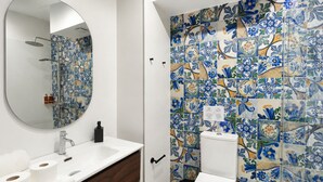 Une salle de bain avec un lavabo blanc, un miroir, des toilettes et un espace douche.