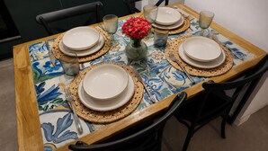 Une table à manger dressée avec des assiettes, des verres et un vase de fleurs.