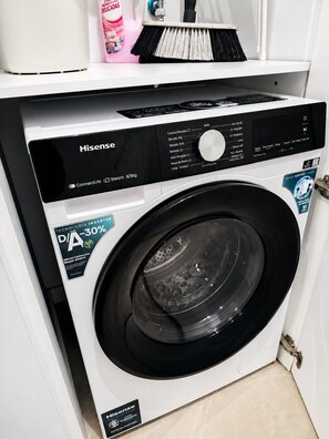 Une machine à laver Hisense à chargement frontal, dotée d’un panneau de commande numérique, d’un indicateur de niveau d’eau et d’un distributeur de détergent.