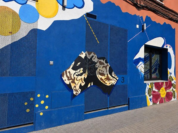 Un bâtiment à la façade bleue, une fenêtre ornée d’une fresque colorée et le chiffre « 3 » peint sur le mur.