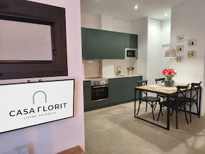 A modern kitchen with green cabinets, a microwave, and a dining area with a table and chairs.