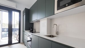 A modern kitchen with dark cabinets, a stainless steel sink, and a built-in microwave.