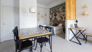 A compact living space with a dining area, a small work desk, and a sofa.