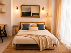 Une chambre d’hôtel avec un lit, des tables de chevet, un miroir, une lampe et une vue sur l’extérieur.
