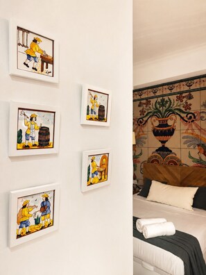 A hotel room with a bed, a wall with framed artwork, and a decorative tile wall. - The Ceramic Homes III  | AC & WiFi | Free Bikes Included (Valencia)