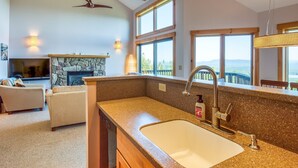 A modern kitchen with granite countertops, a large sink, and a stone fireplace.