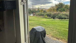 Vista desde una habitación con ventana que da a una zona verde y una masa de agua.
