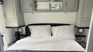 Una cama con colcha a cuadros blancos y negros, un cabecero con espejo y una mesita de noche con lámpara.