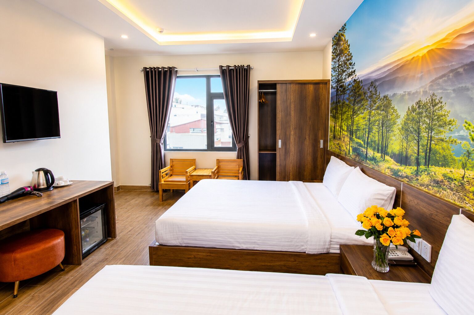 Une chambre d’hôtel avec un lit, un bureau, une chaise et un tableau représentant un paysage forestier.