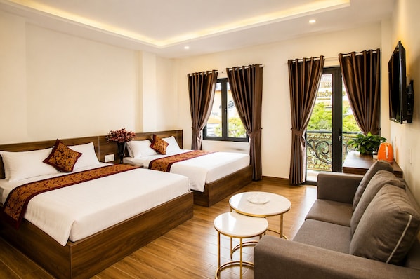 Une chambre d’hôtel avec deux lits, un canapé, une petite table et un téléviseur.