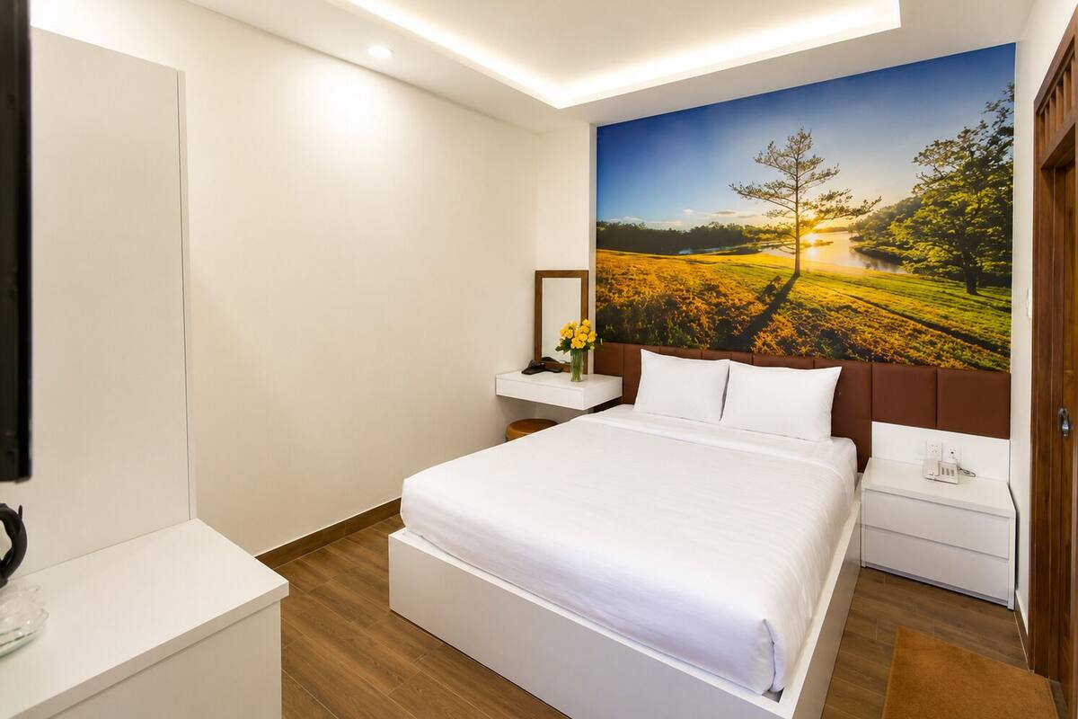 A hotel room with a bed, a nightstand, a mirror, and a large wall mural.