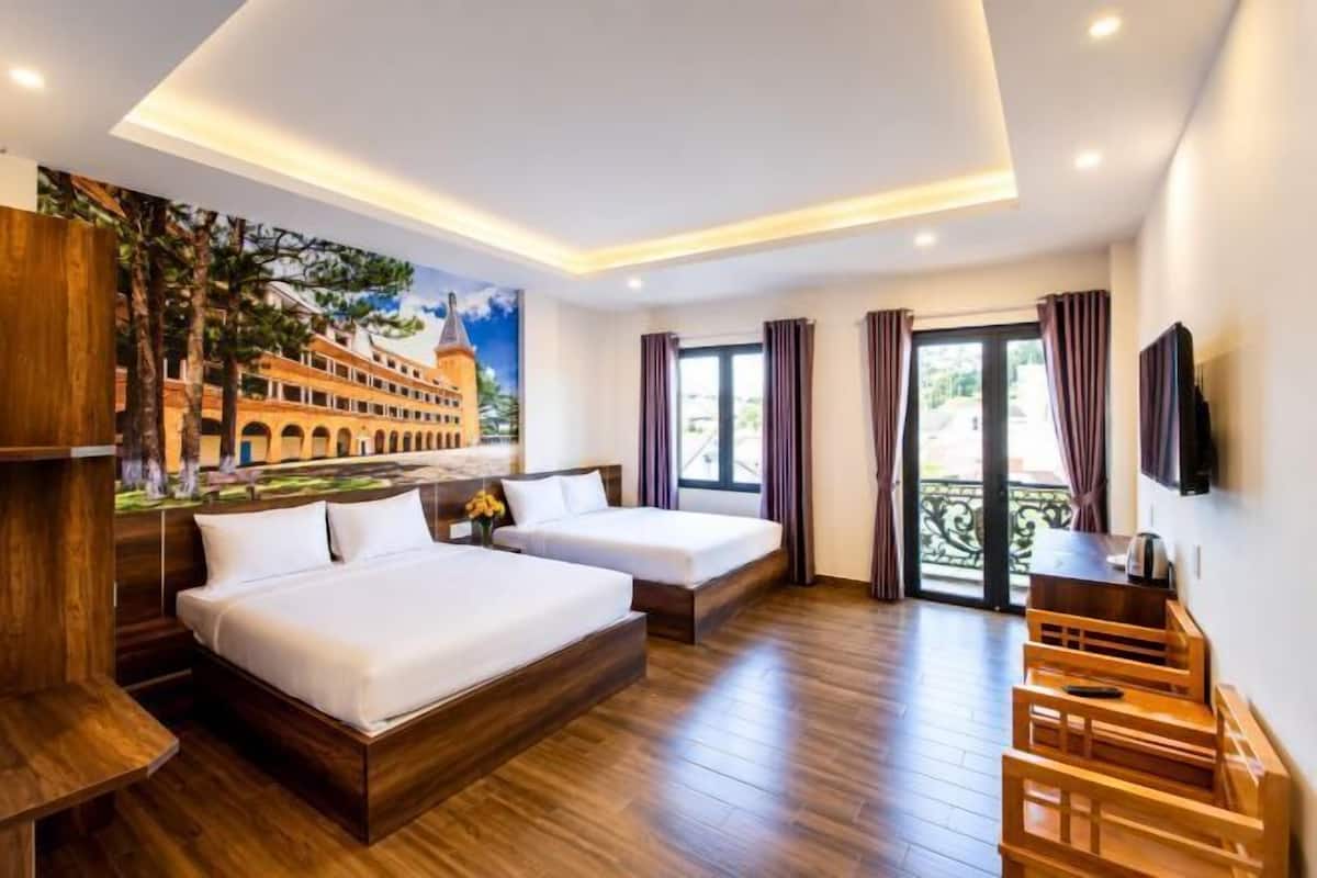 A hotel room with two beds, a wooden floor, a mural, and a balcony with curtains.