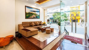 A modern lobby with a sofa, ottomans, a coffee table, and a painting on the wall. - Lien's Hotel Da Lat (Xuan Huong - Da Lat)