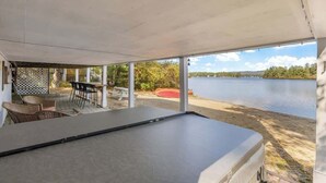 An outdoor deck with a pool table, chairs, and a table, overlooking a lake. - Lake Home with Private Beach and Hot Tub (Ossipee)