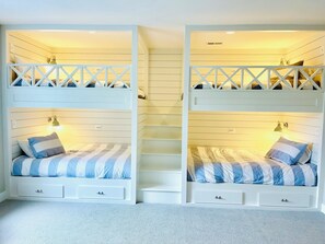 A room with two bunk beds, each with a small desk and a lamp.