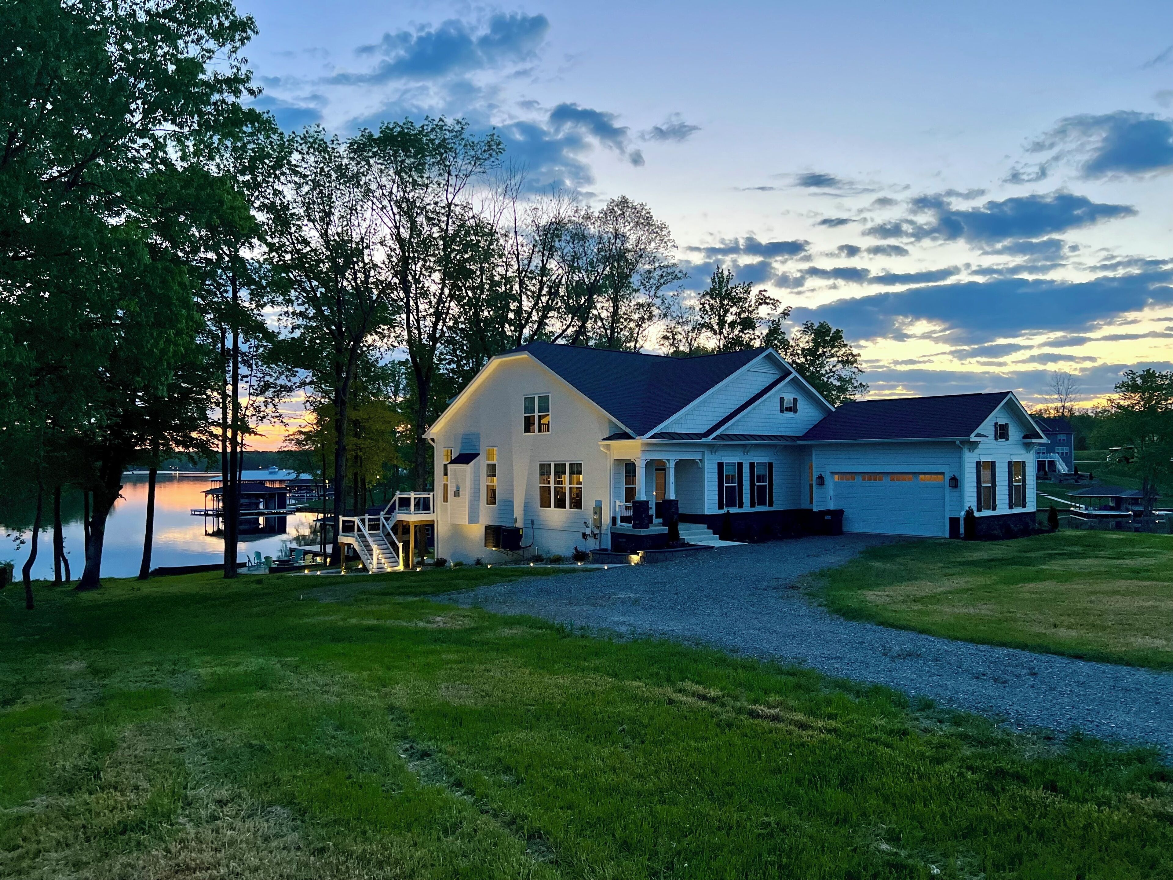 A two-story house with a dock, a covered deck, and a driveway leading to the garage.