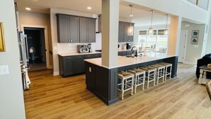 A spacious kitchen with a central island, dark cabinetry, and a wooden floor.
