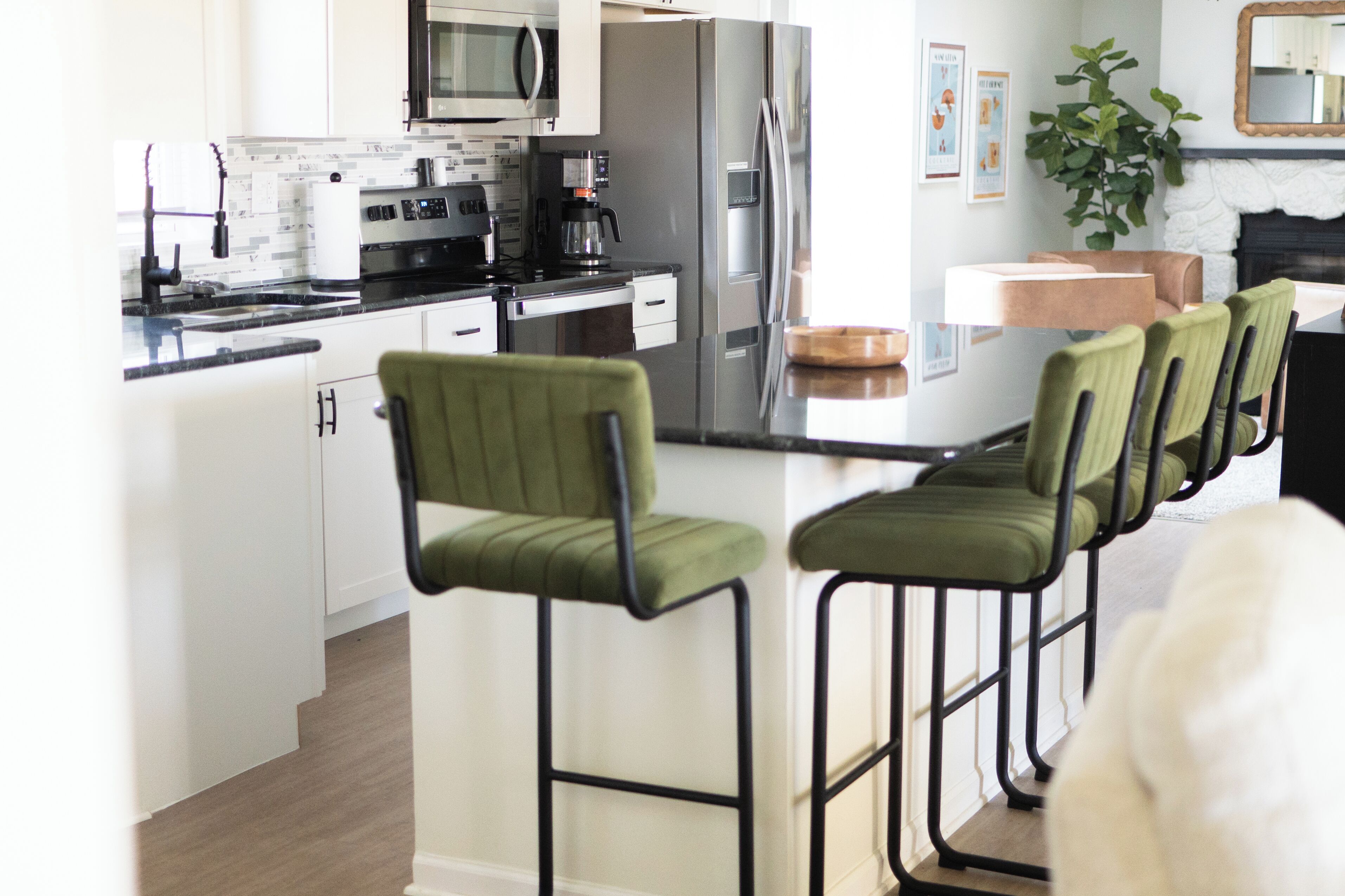 Una cocina moderna con electrodomésticos de acero inoxidable, una isla central con taburetes de bar y un comedor con chimenea.