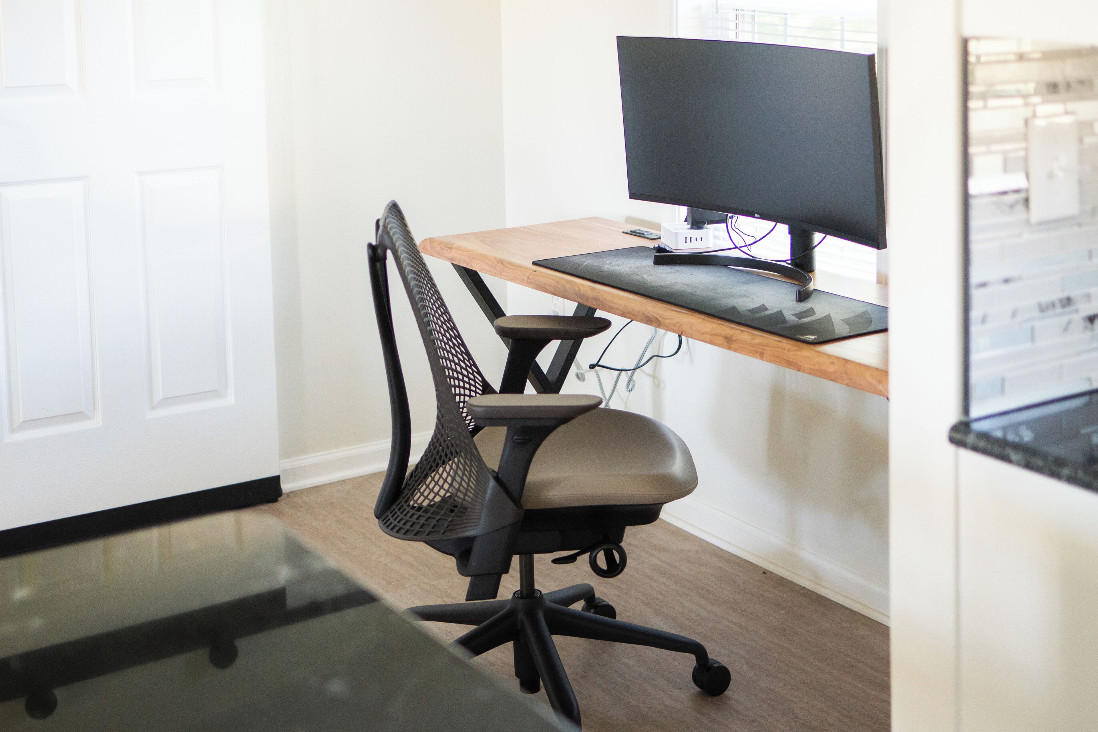A modern office space with a wooden desk, a black mesh office chair, and a computer monitor.