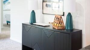 A dark wood console table with two teal lamps, a white tray, and a wooden sculpture. - Charming 3-bedroom Ranch Home in Grand Rapids - Perfect for Family Getaways! (Grand Rapids)
