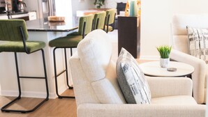 A modern living room with a sofa, a small round table, and green chairs. - Charming 3-bedroom Ranch Home in Grand Rapids - Perfect for Family Getaways! (Grand Rapids)