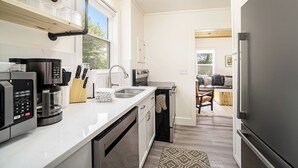 A modern kitchen with stainless steel appliances, a built-in oven, and a coffee maker. There is a window providing natural light and a view of the outdoors. - Newly renovated downtown apartments with parking (Douglas)
