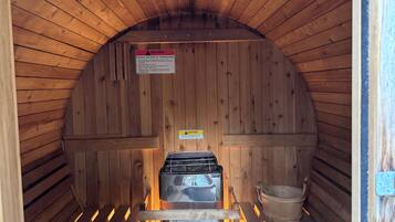 Een sauna met houten wanden en een bankje. Er is een waarschuwingsteken om het risico op oververhitting te verminderen.