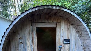 A rustic wooden sauna with a door, a wooden bench, and a small wooden tub. - Private Romantic Woodland Getaway- sauna, hot tub, outdoor culinary bar, gardens (Vader)